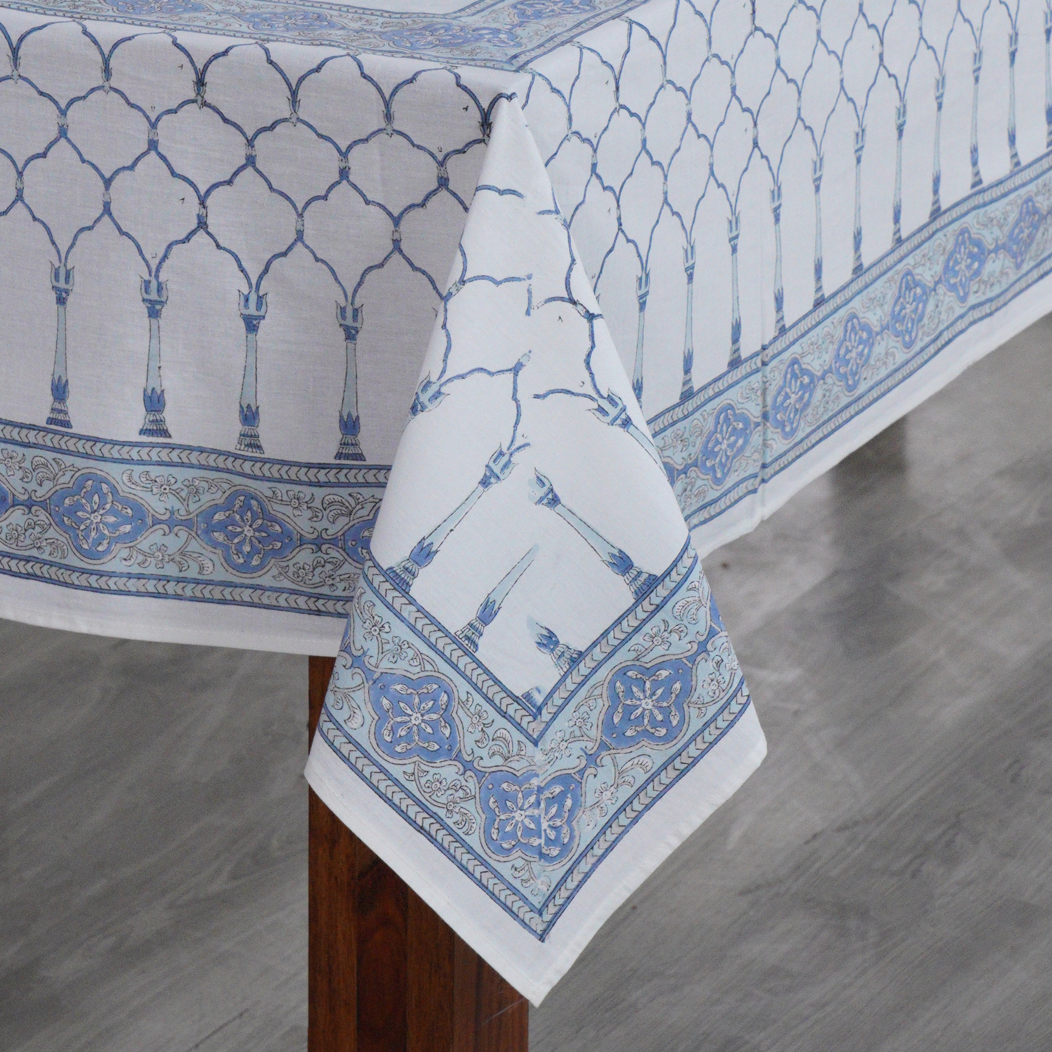 Blue and white patterned tablecloth on a wooden table with a gray floor background