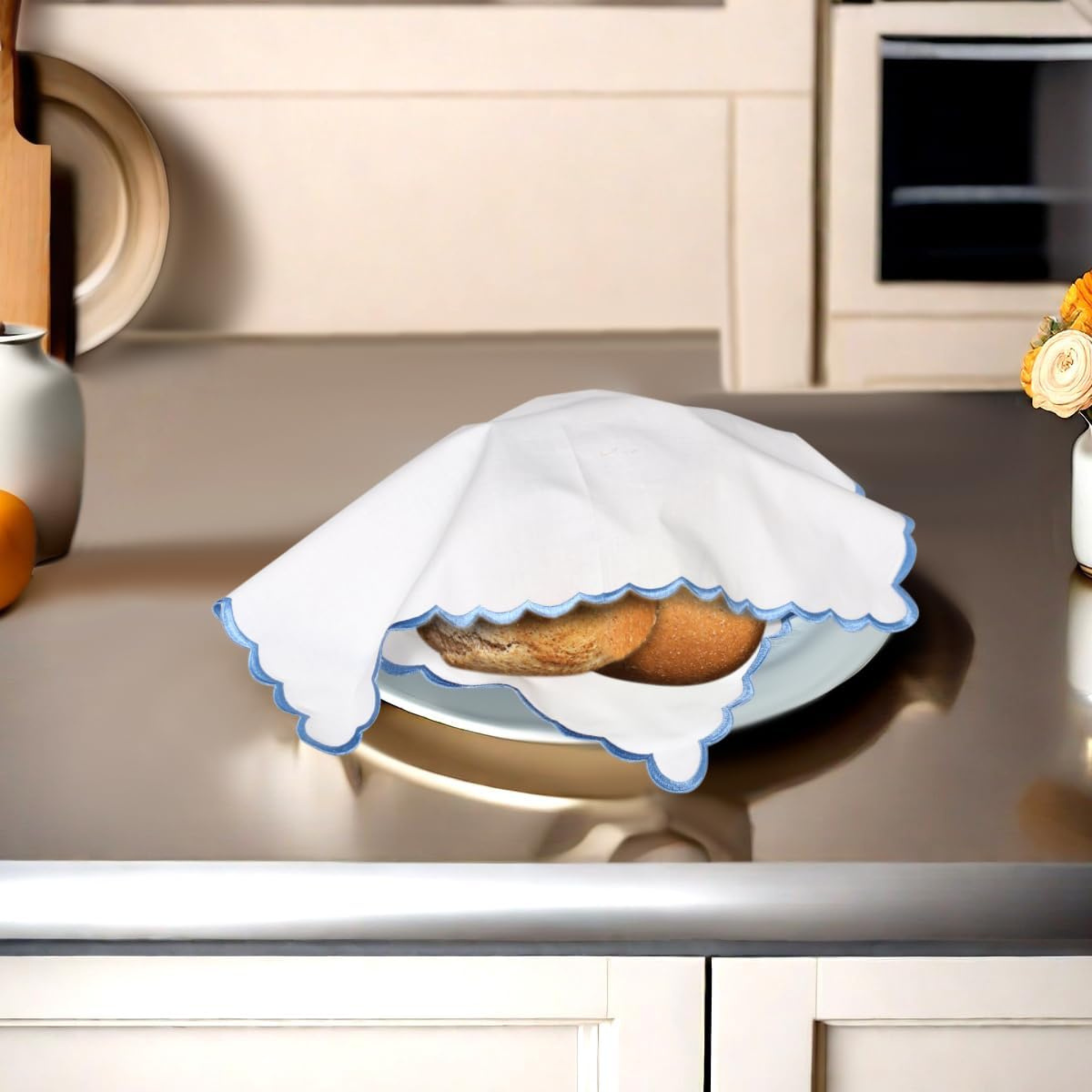 Baked goods on a plate with a white cloth draped over it on a kitchen counter.