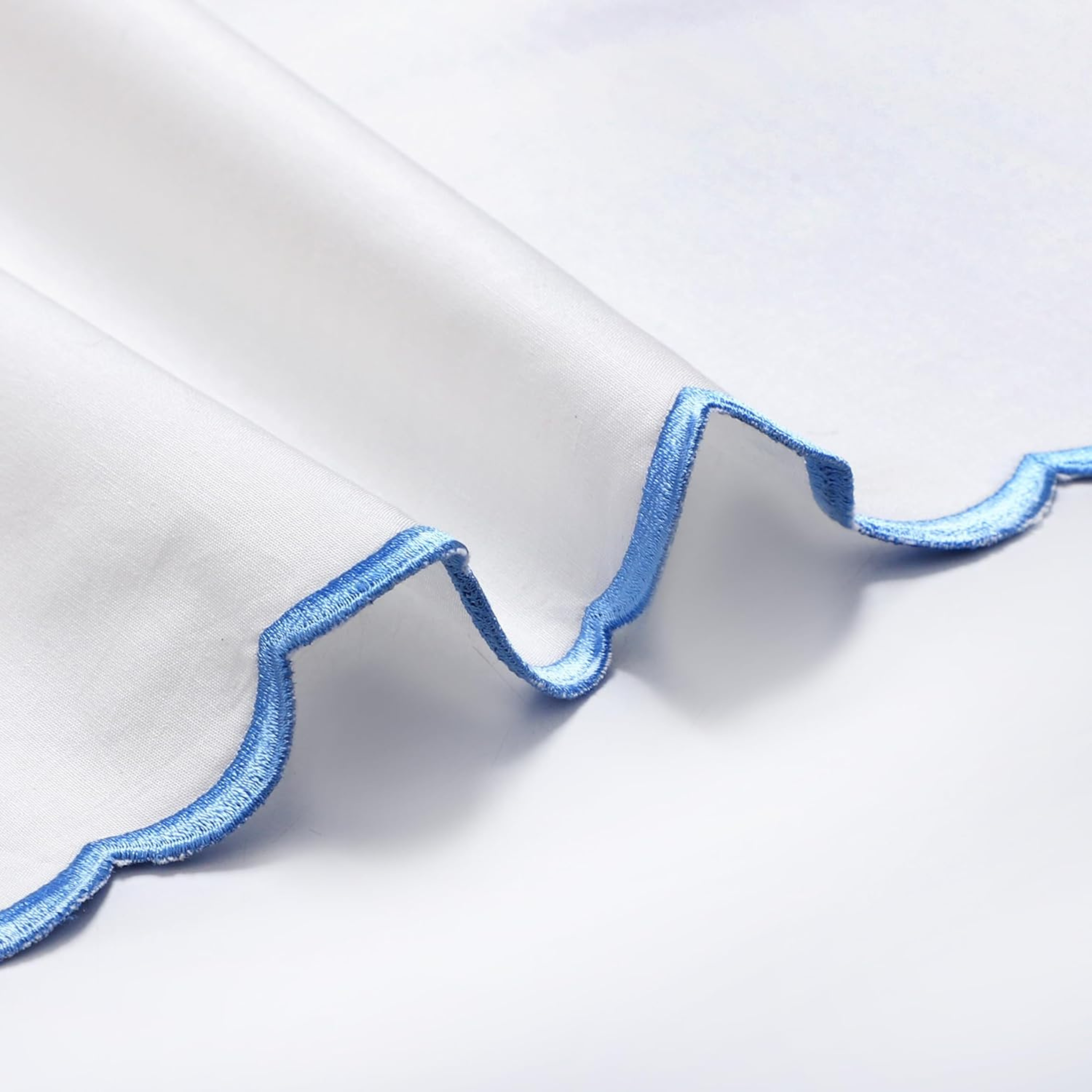 Close-up of a white shirt with blue trim on a light gray background
