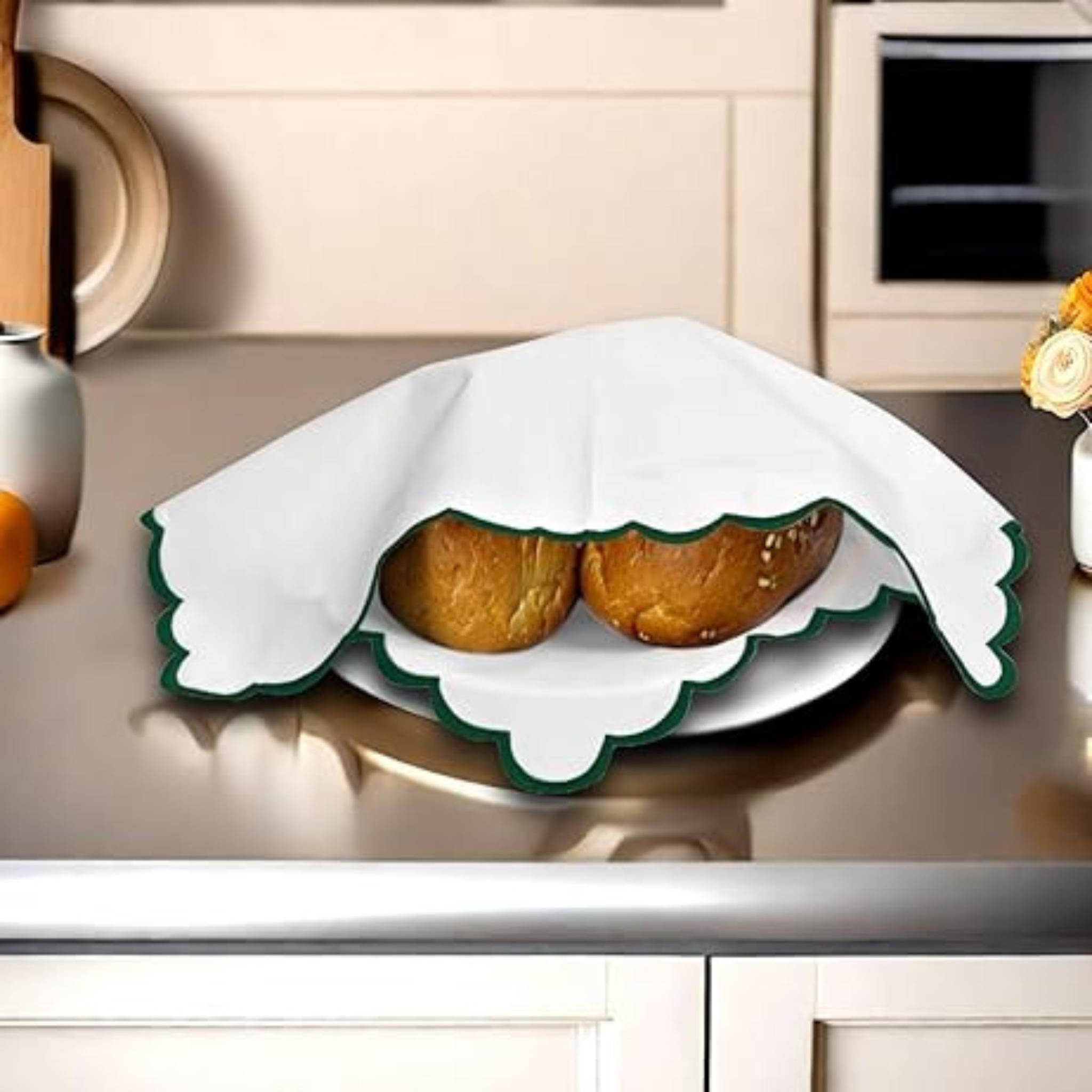 Two baked goods on a decorative plate with a white cloth draped over it, set against a kitchen counter.