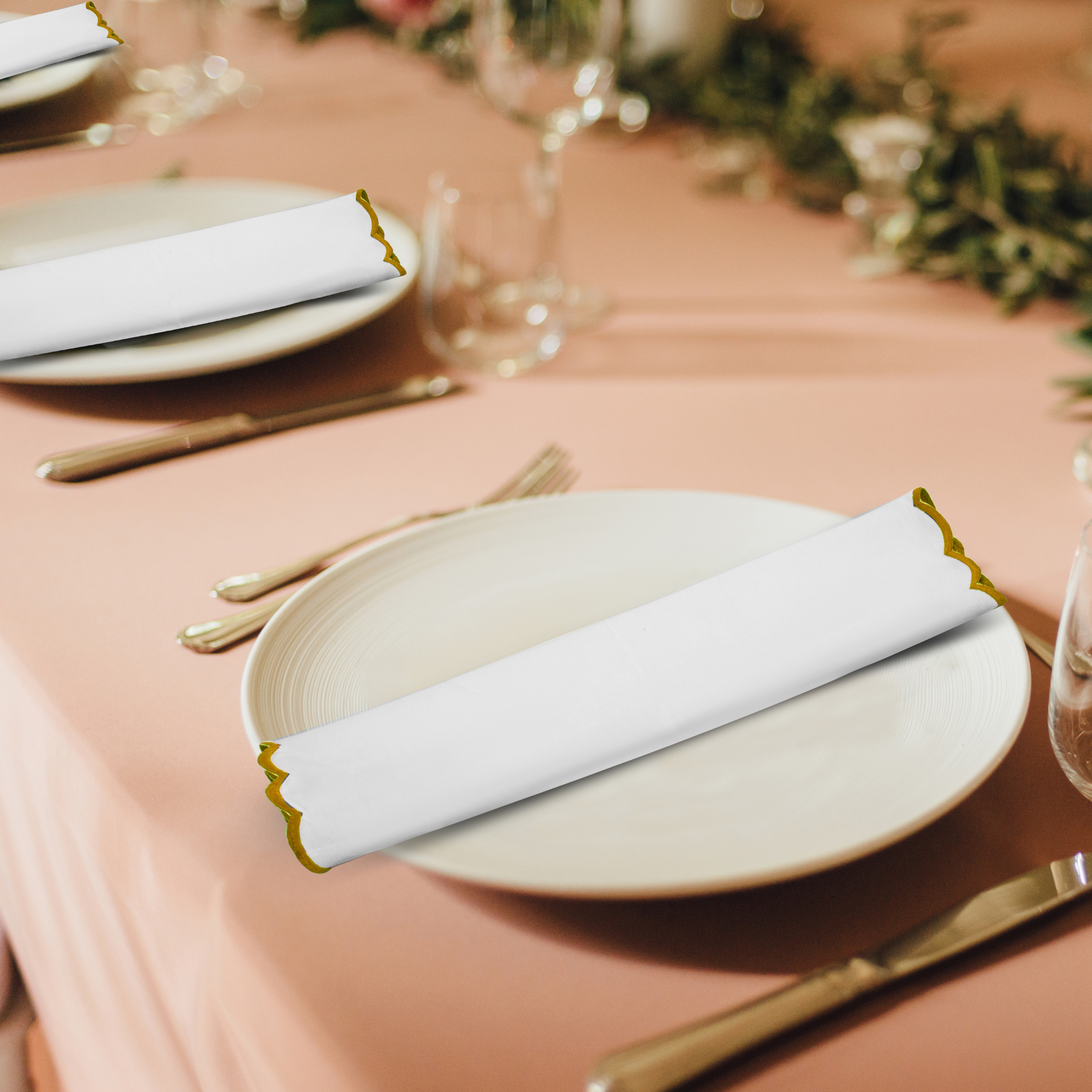 Elegant table setting with plates, napkins, and cutlery on a pink tablecloth.