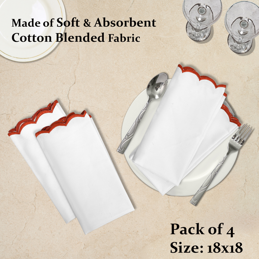 Set of white napkins with red scalloped edges on a beige surface with cutlery.