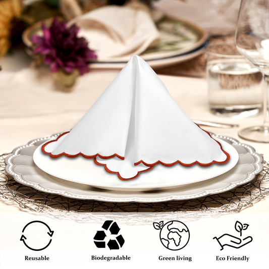 White scalloped napkin holder on a decorative plate with table setting in the background