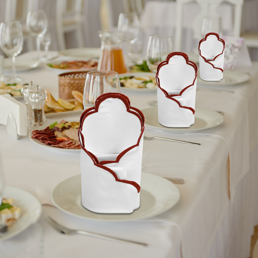 Decorative white napkins with red borders on a table setting.