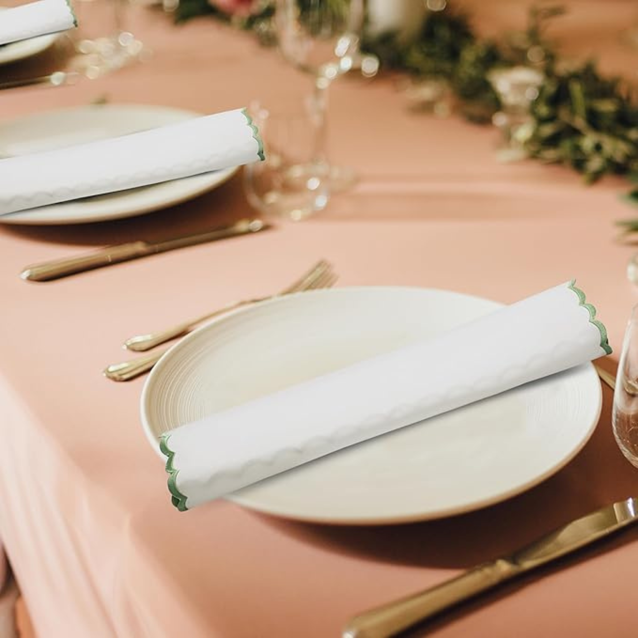 Elegant table setting with plates, napkins, and cutlery on a pink tablecloth.