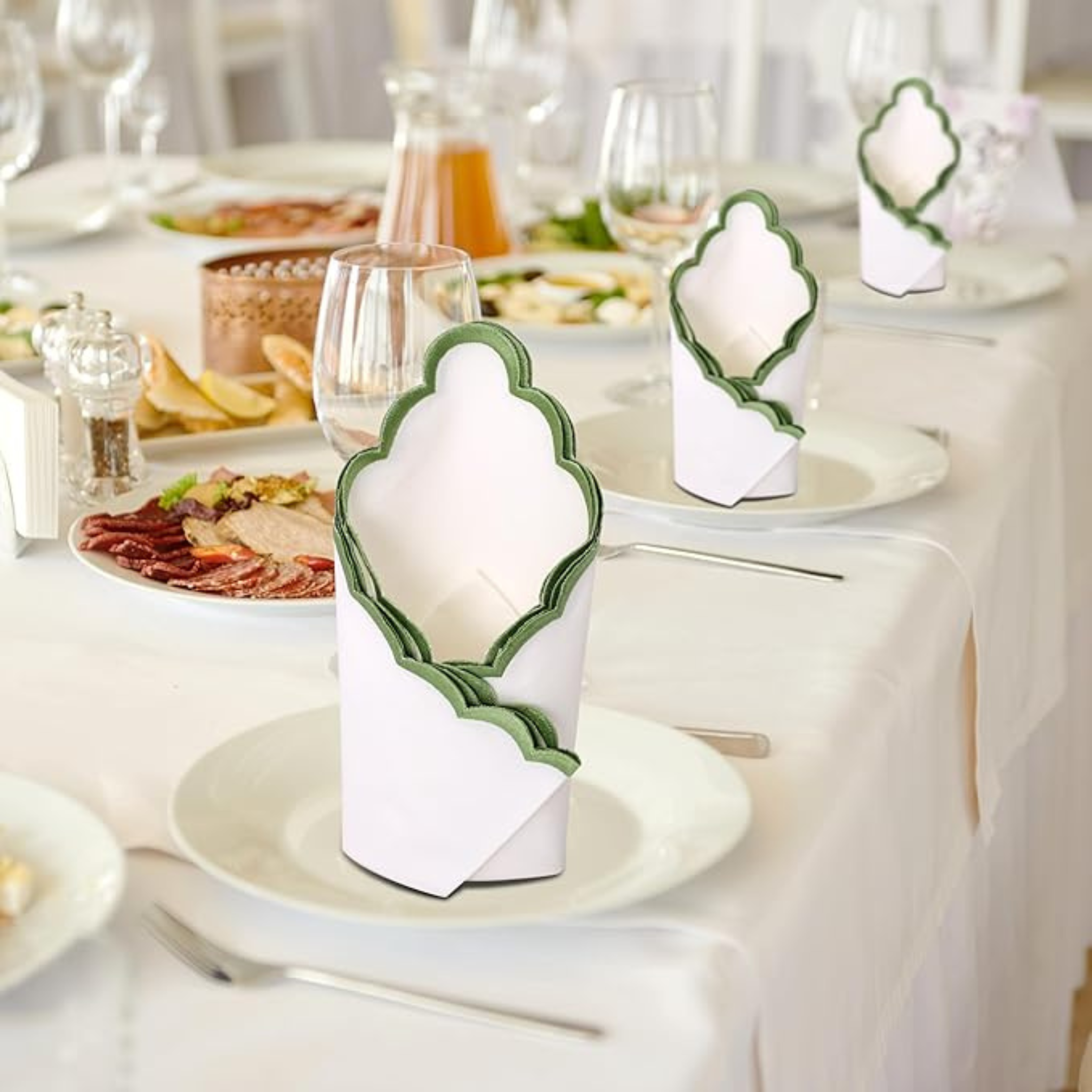 Decorative white and green place cards on a table with food and glasses.