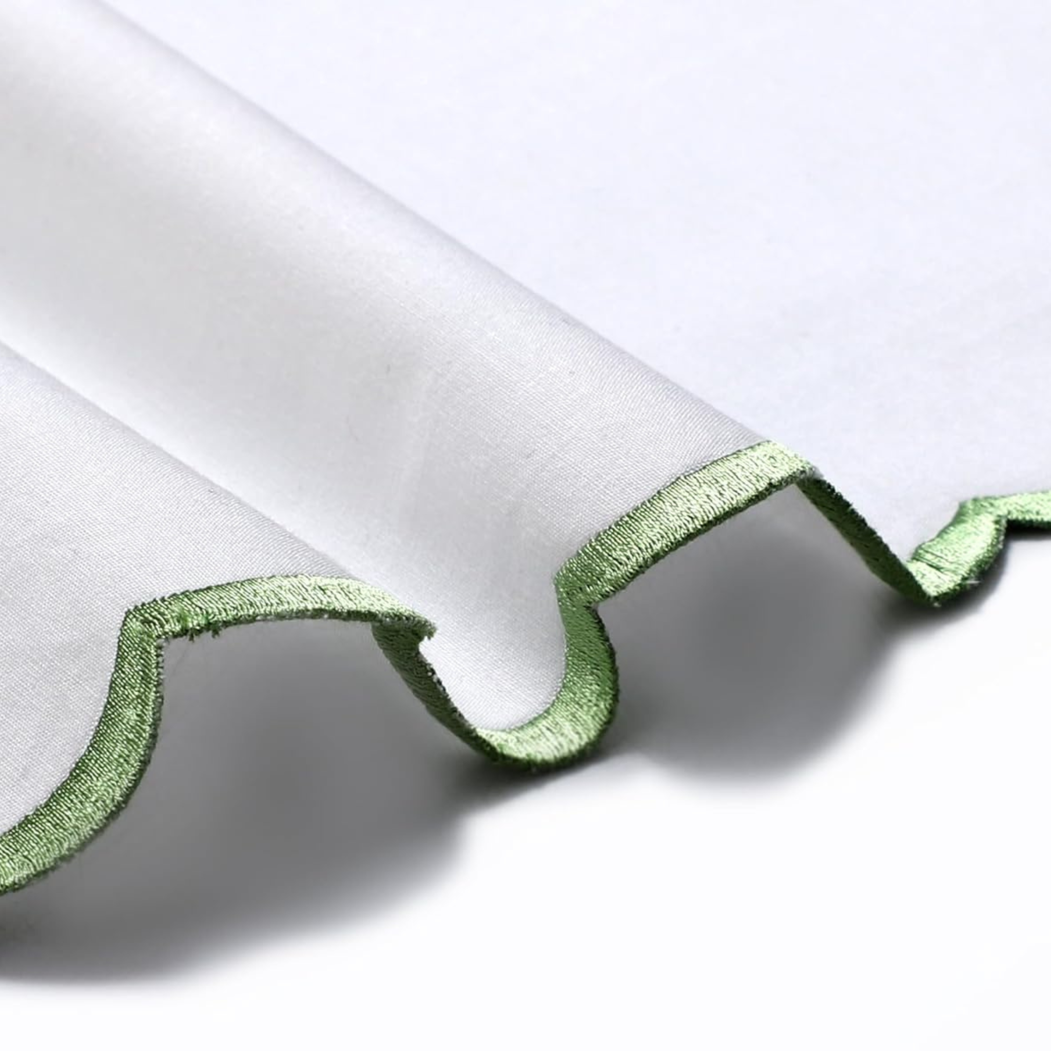 Close-up of white fabric with green trim on a white background