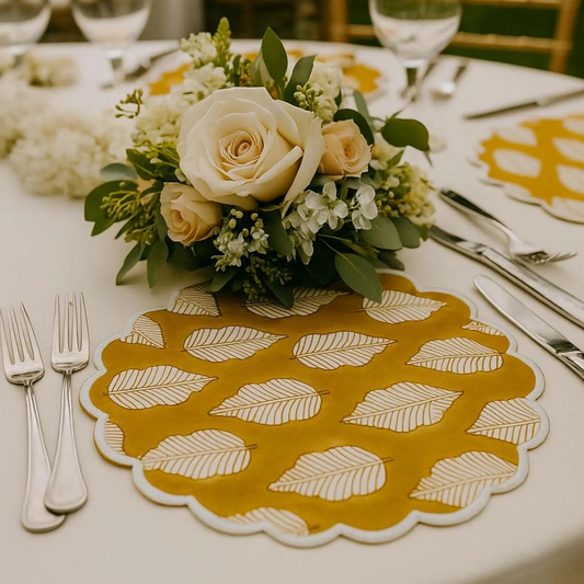 Table setting with a floral arrangement, yellow leaf-patterned placemat, and silverware.