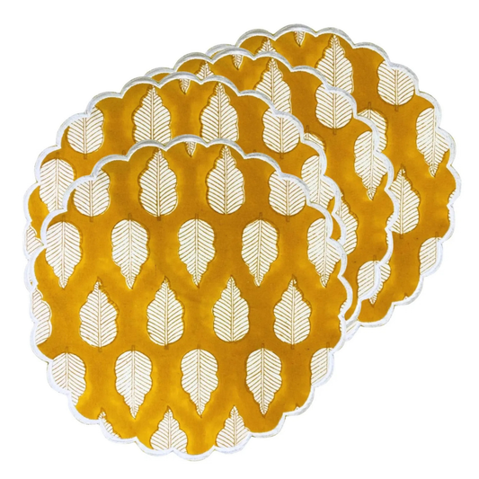 Set of four yellow placemats with white leaf pattern on a white background